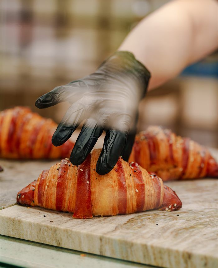 A gloved hand placing croissants on marble