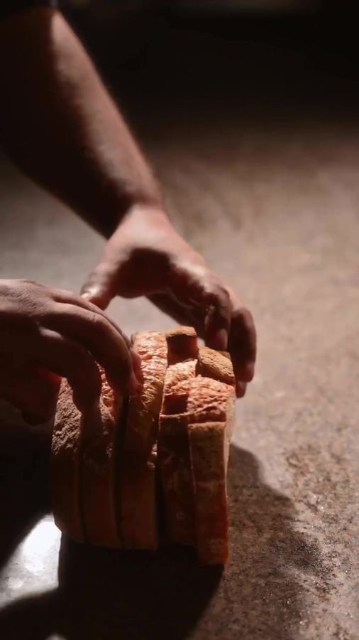 Hands slicing a loaf of bread
