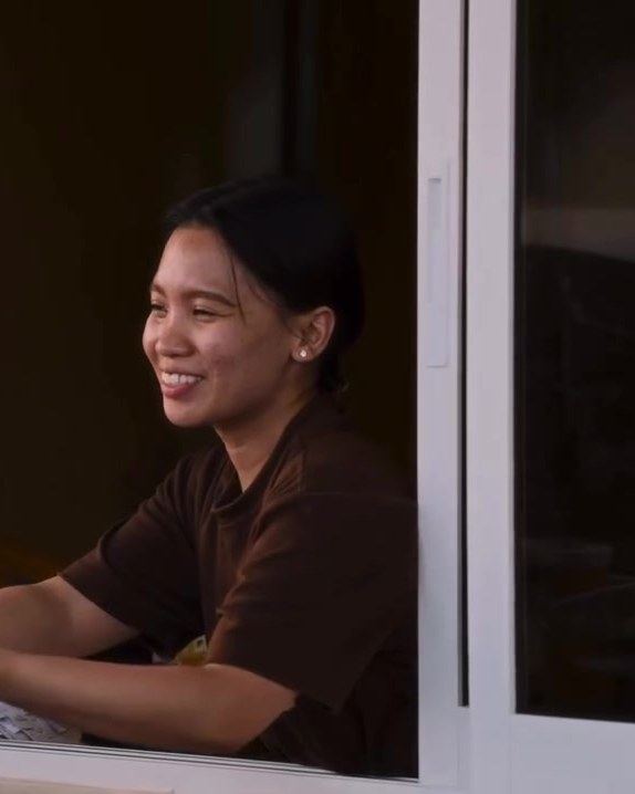 A smiling staff member at the drive-thru window